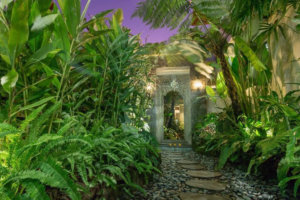 A stone pathway leading to an ornate archway surrounded by lush greenery.