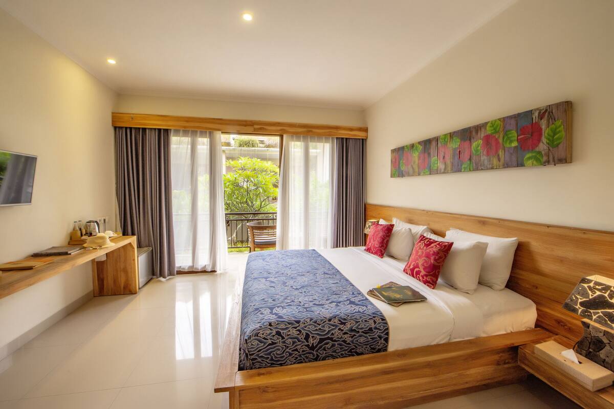 A bedroom with a large bed, wooden headboard, and a painting on the wall.