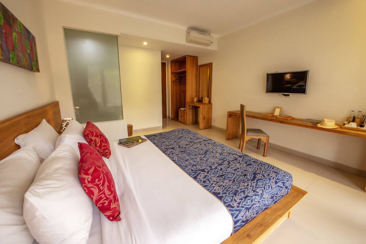A hotel room with a bed, a desk, a TV, and a wardrobe.