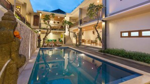 A modern building with a central pool, multiple balconies, and indoor plants. - Jani's Place Cottage (Ubud)