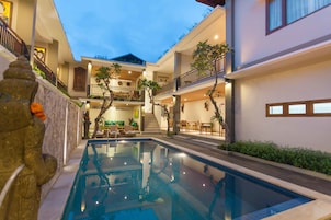 Un edificio moderno con piscina central, varios balcones y plantas de interior.