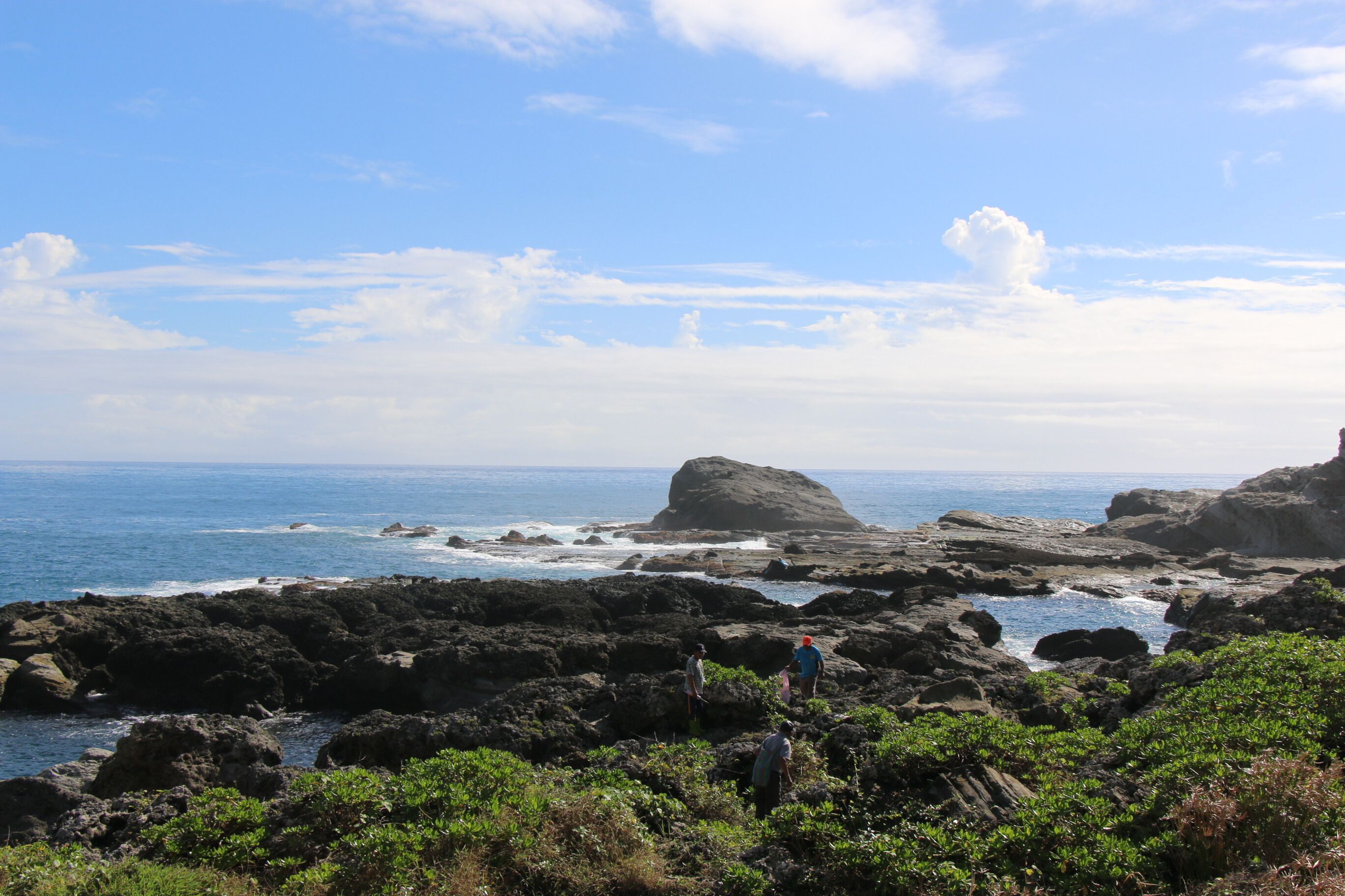 A rocky coastal landscape with clear skies and a view of the ocean.