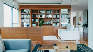 A modern living room with a wooden bookshelf, a white sofa, and a blue armchair. - Adagio Shitiping (Fengbin)