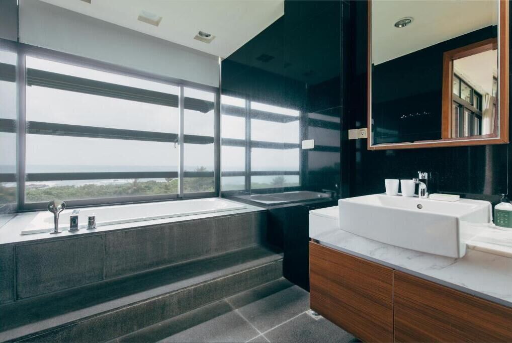 A modern bathroom with a large window, a sink, and a mirror.