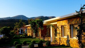 Un bâtiment en pierre avec un jardin et une montagne en arrière-plan.