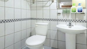 Een badkamer met toilet, wastafel en een plank met toiletartikelen.