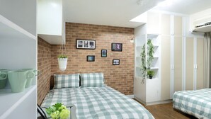 Een slaapkamer met een bakstenen muur, een bed met geruit beddengoed, een hangplant en een kledingkast.
