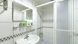 Een badkamer met een wit wastafel, een spiegel en een douchecabine.