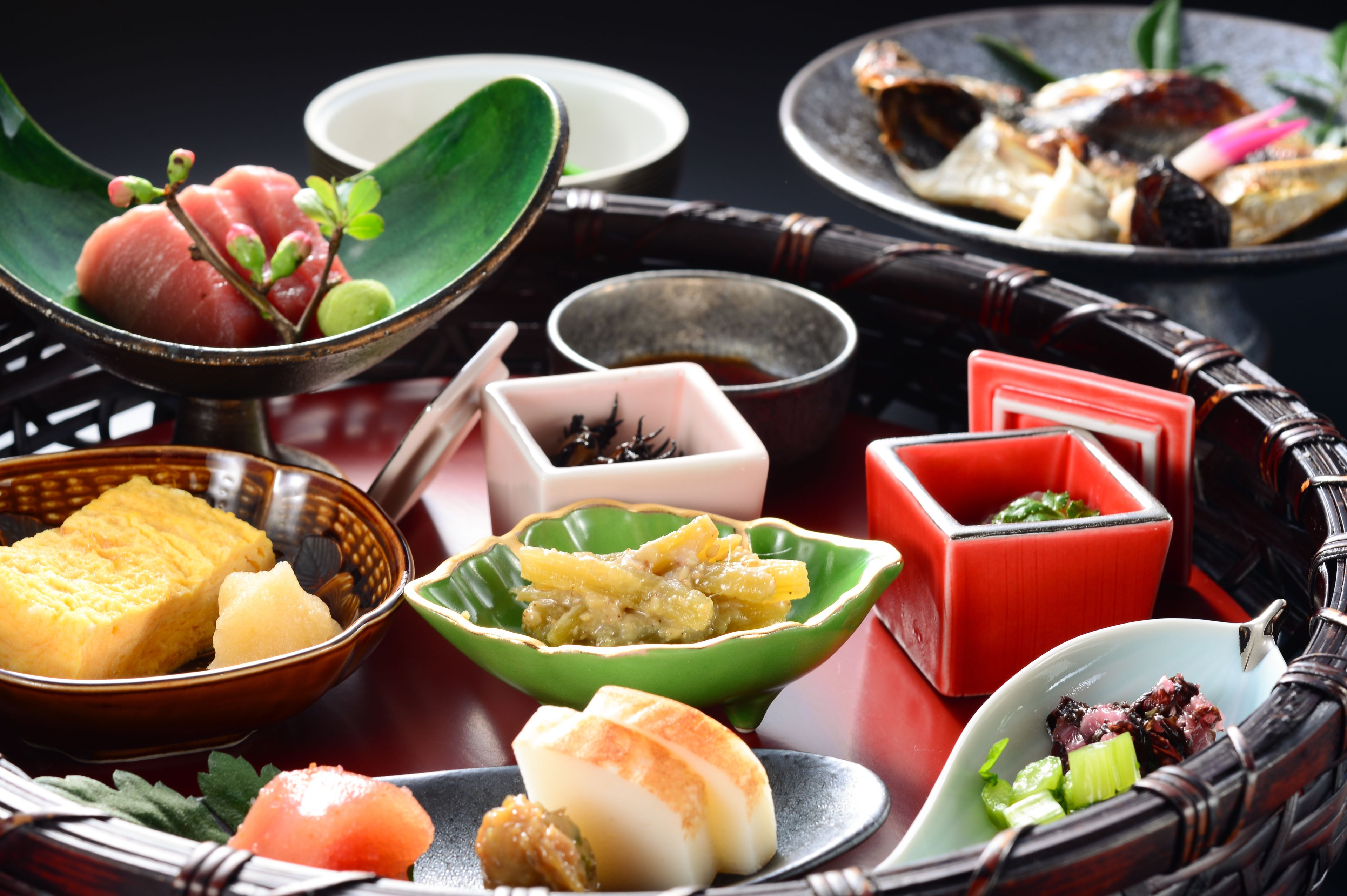 A variety of Japanese dishes arranged on a traditional table with multiple bowls and plates.