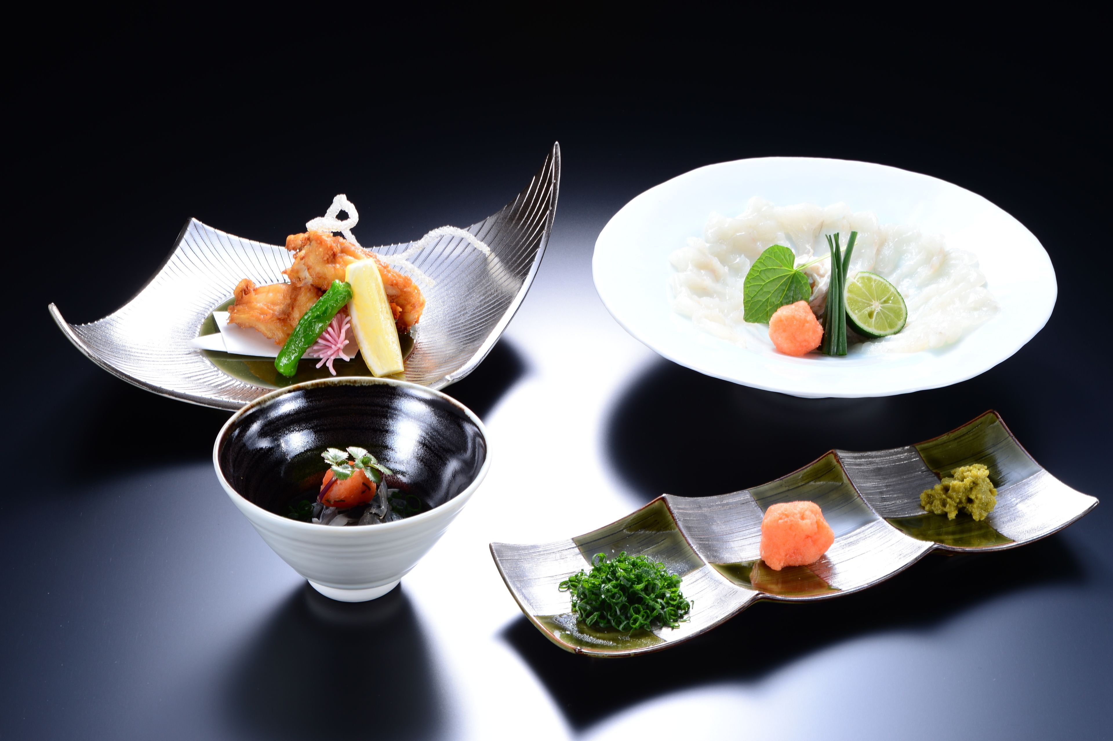 A variety of Japanese dishes including tempura, rice with fish, and sashimi on a dark background.