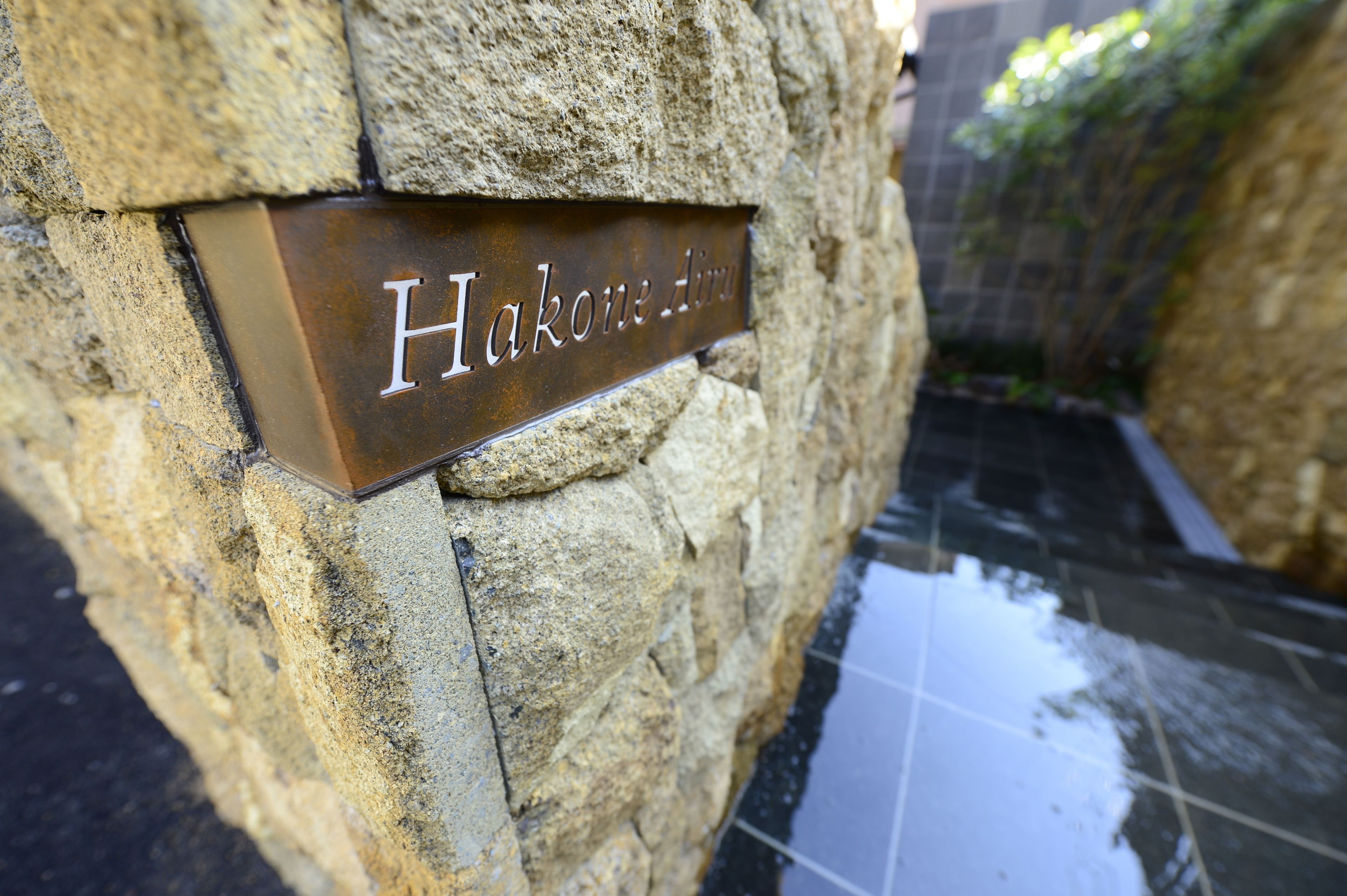 A metal plaque with the inscription "Hakone Air" mounted on a stone wall.