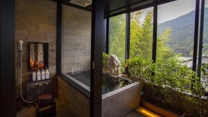 A modern bathroom with a stone wall, a large window, and a view of a mountainous landscape. - Hakone Airu (Hakone)
