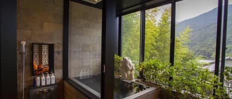 A modern bathroom with a stone wall, a large window, and a view of a mountainous landscape.