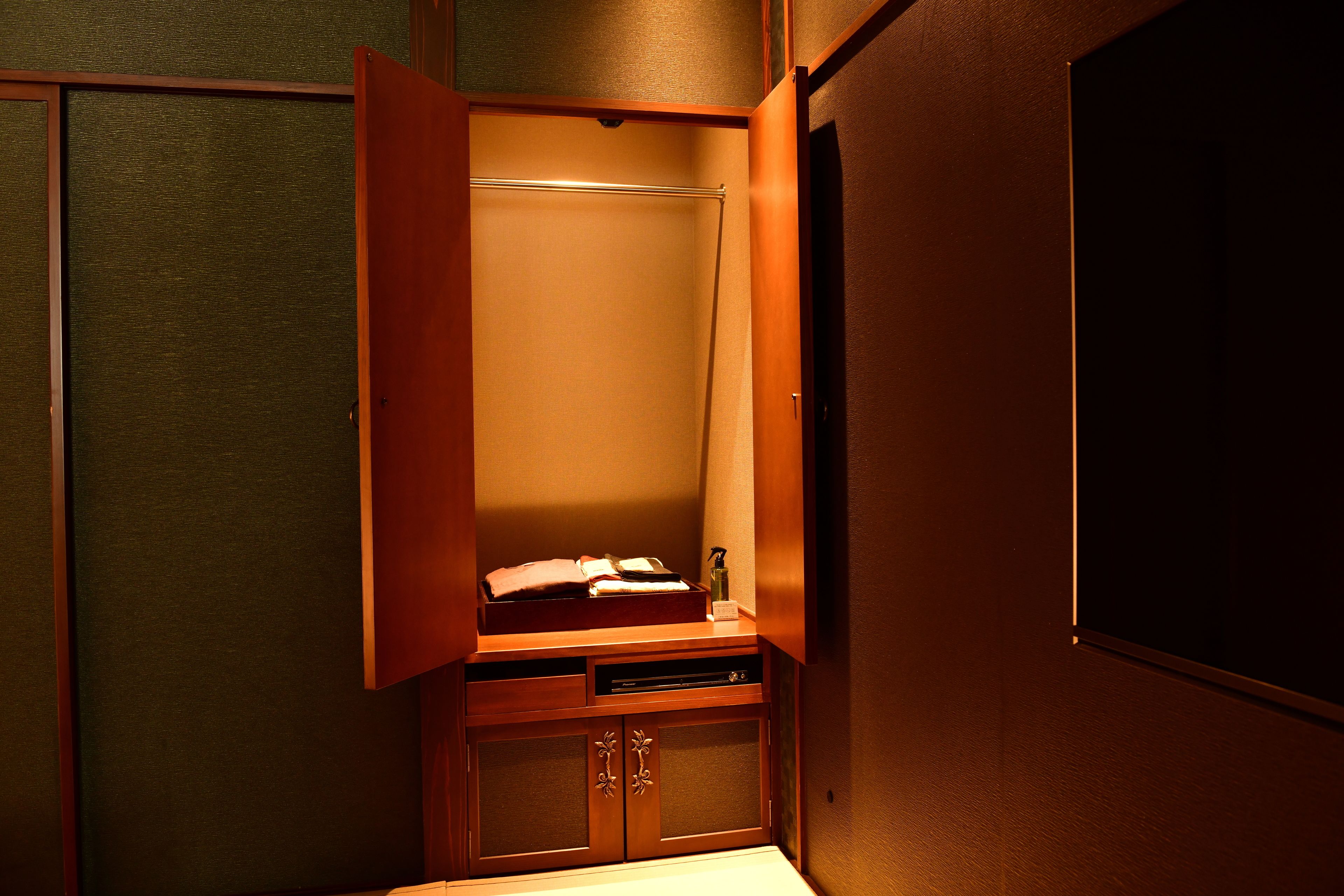 A compact room with a wooden cabinet, a small shelf with toiletries, and a mirror.