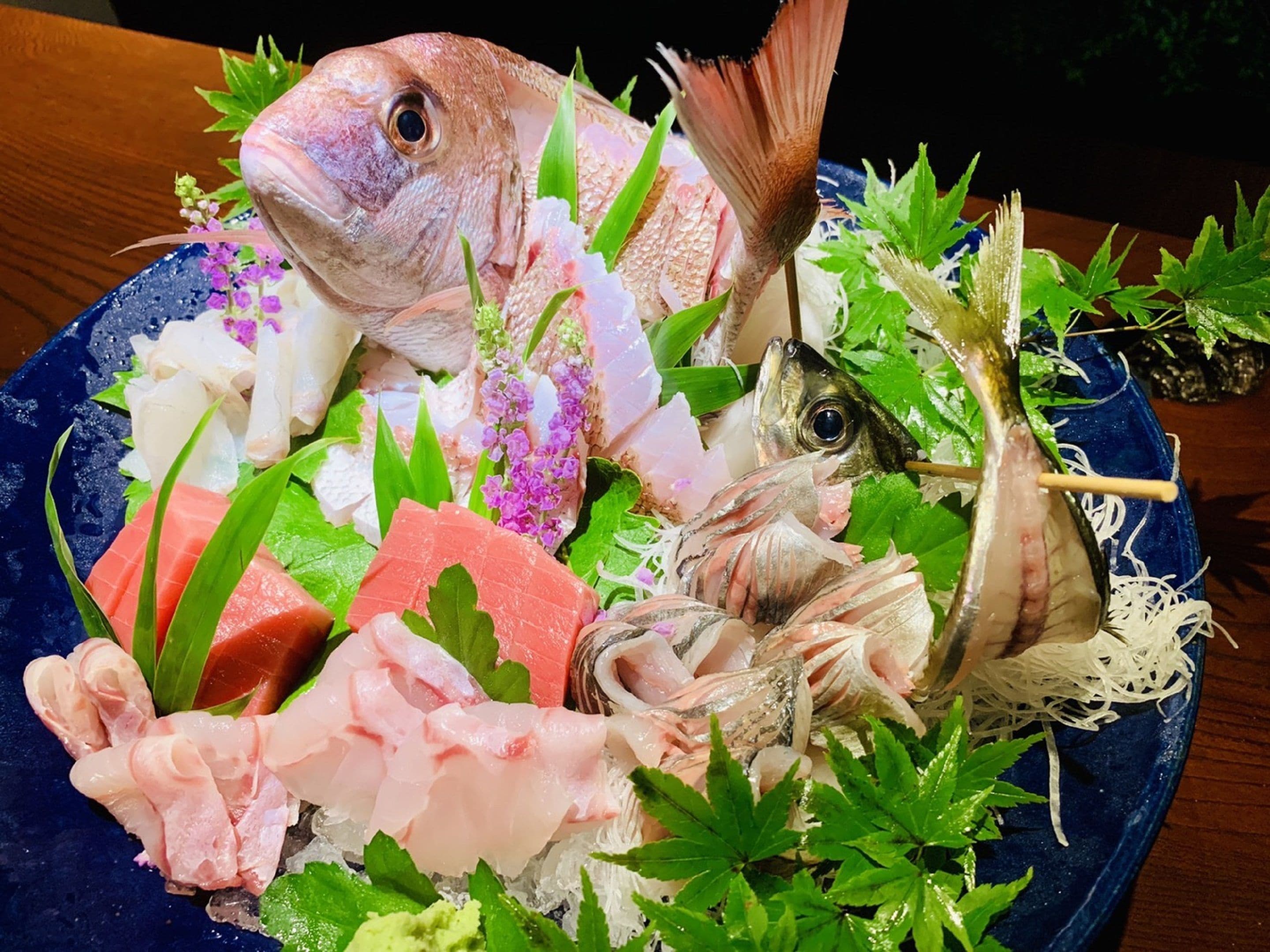A seafood platter with various fish and garnishes on a blue plate.