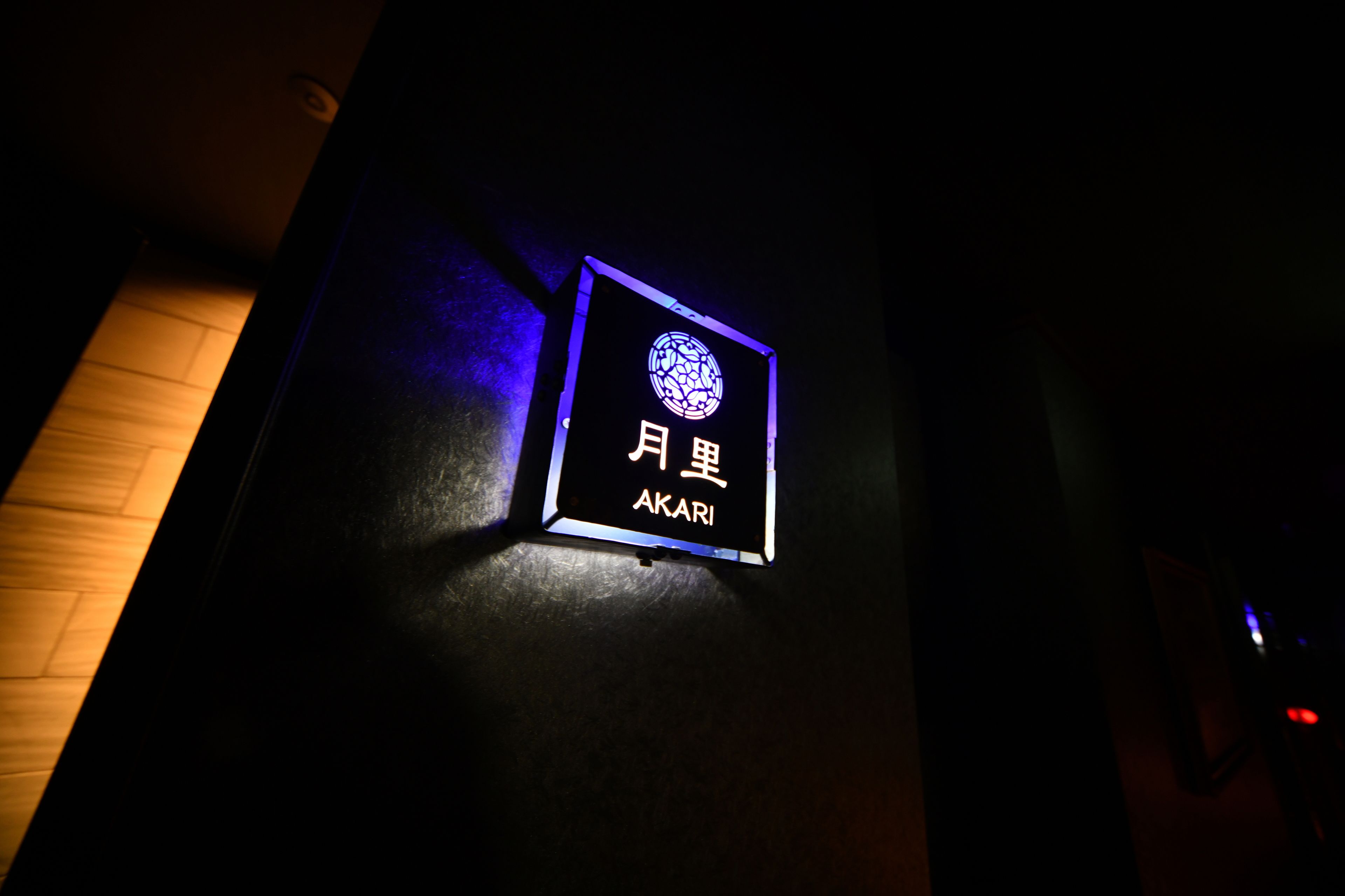 A dark room with a sign that reads "AKARI" in English and Japanese characters.