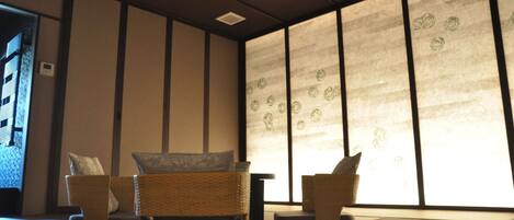 A traditional Japanese-style room with tatami flooring, low wooden furniture, and sliding shoji screens.