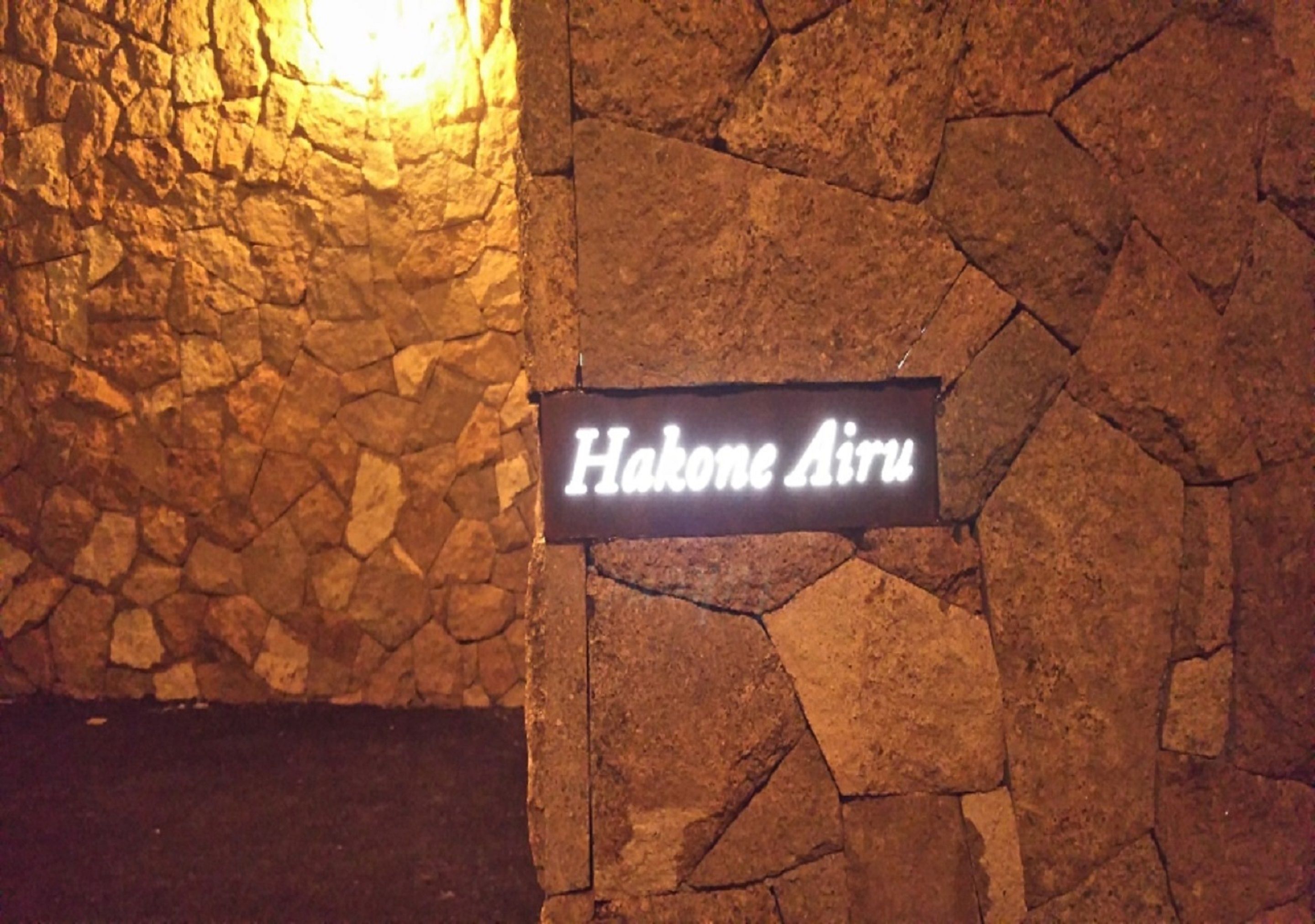 Un muro de piedra con un cartel que dice "Hakone Airu".