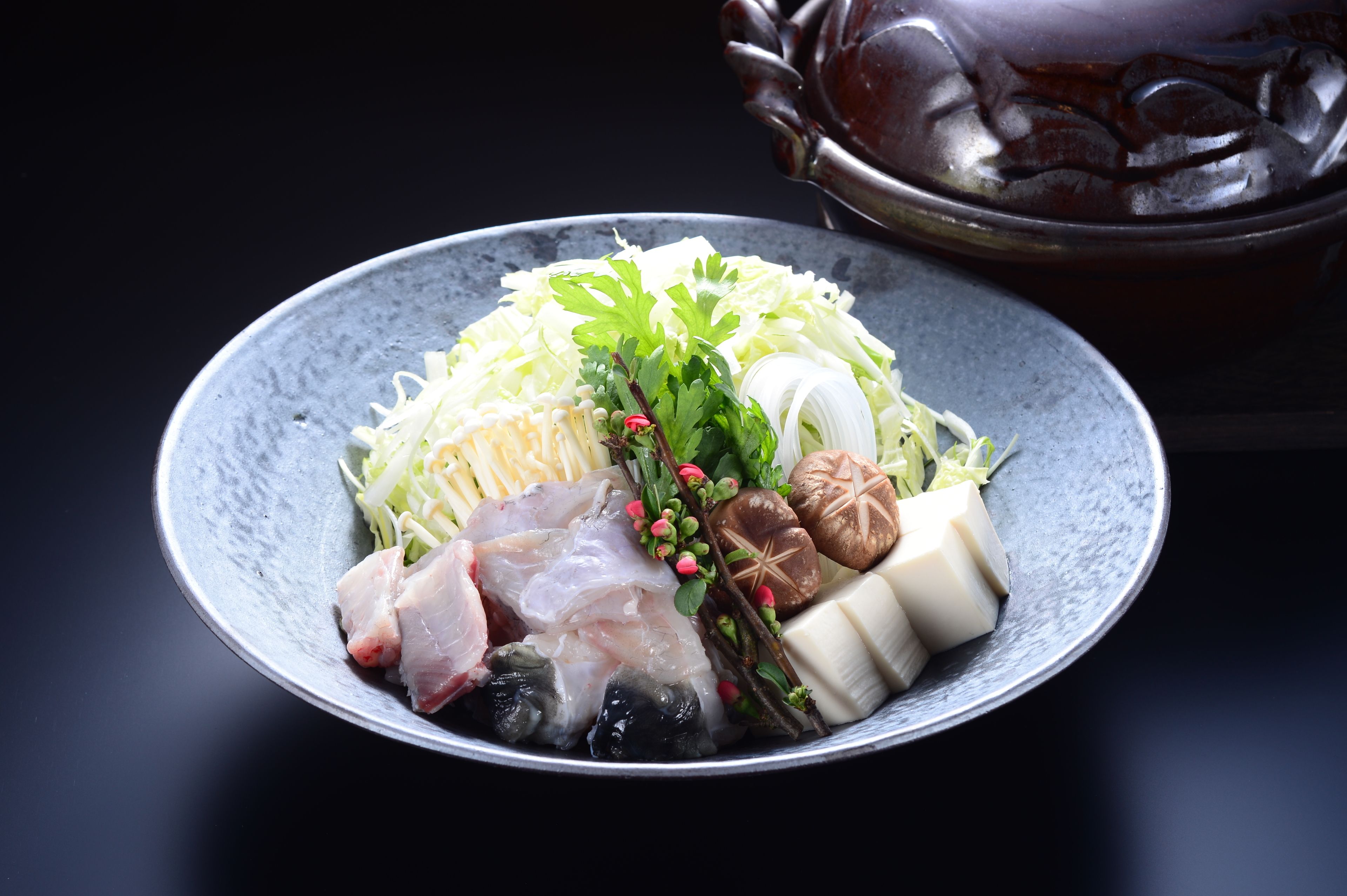 A bowl of assorted raw seafood and vegetables on a plate.