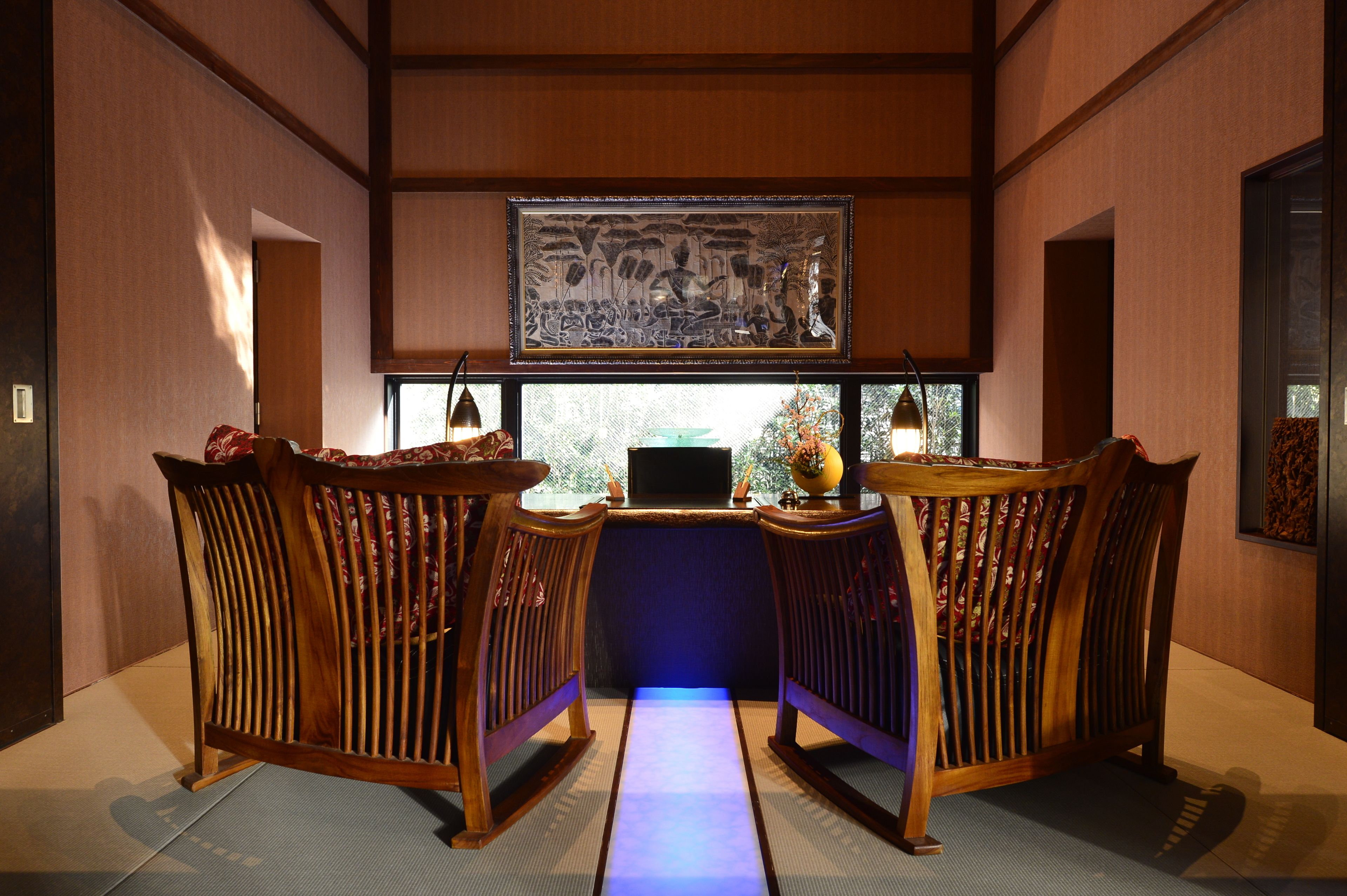 A traditional Japanese room with tatami flooring, a low table with a laptop, and two wooden chairs.