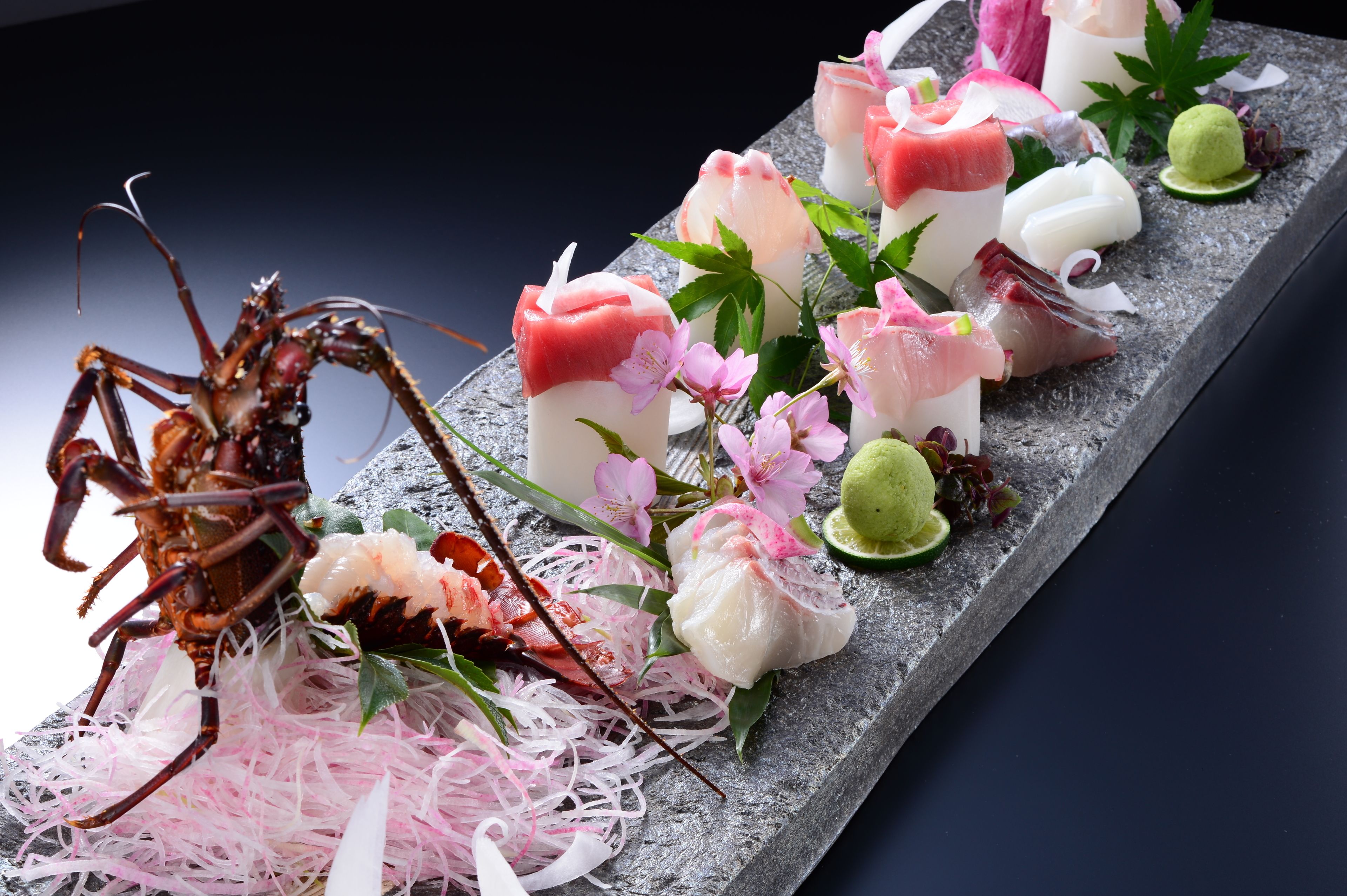 A seafood platter with various types of fish and garnishes on a stone surface.