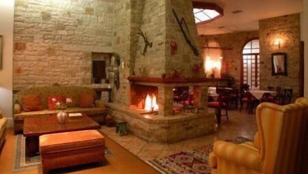 A stone-floored living room with a fireplace, a sofa, and a dining area with chairs.