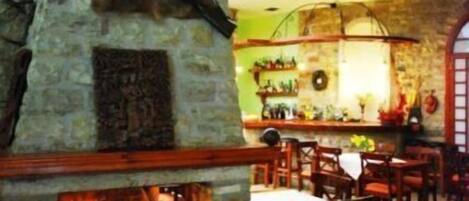 A rustic interior with a stone fireplace, wooden furniture, and a high ceiling with a skylight.