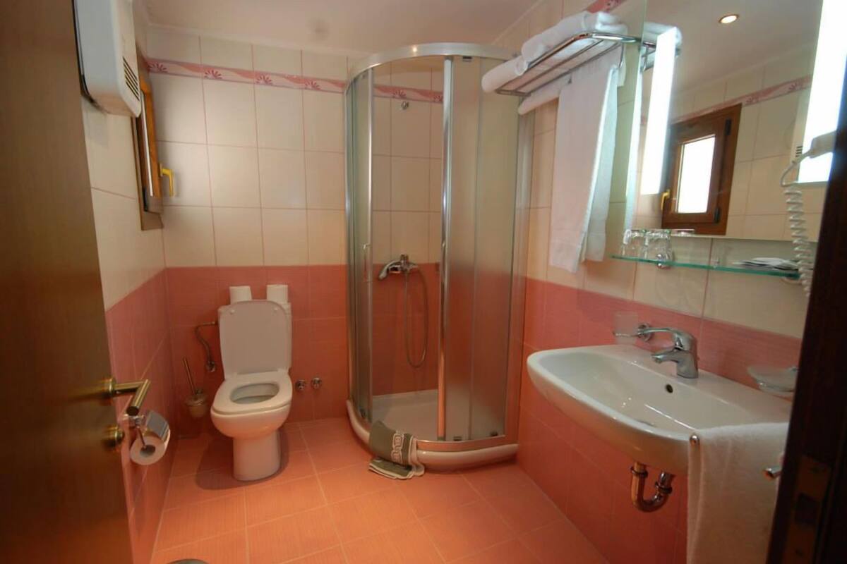 Un baño con inodoro, ducha con mampara de vidrio y lavamanos.