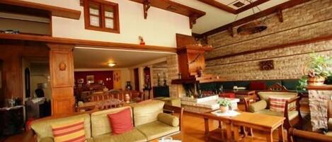 A cozy living room with a wooden ceiling, a sofa, a dining table, and a fireplace.