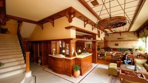 A spacious lobby with a grand staircase, a reception desk, and comfortable seating areas.