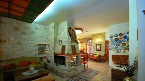 A cozy living room with a stone fireplace, a sofa, and a dining area with a table and chairs.
