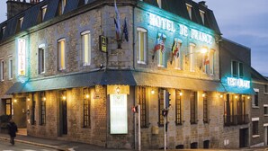 Un edificio de piedra histórico con entrada en esquina, un letrero de restaurante y banderas.
