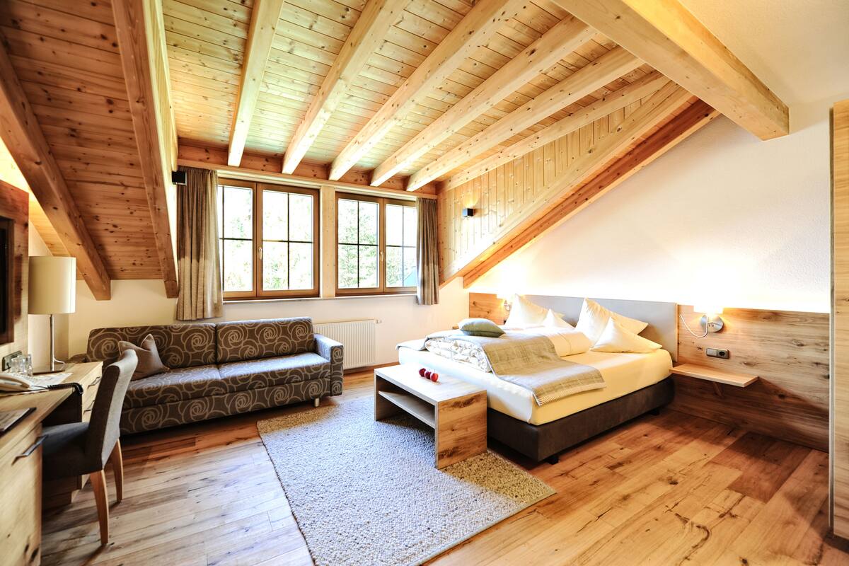 Un dormitorio estilo loft acogedor, con techo de madera, cama, sofá y escritorio.