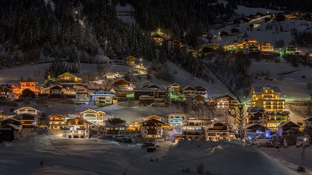 A snow-covered village with brightly lit buildings, likely a ski resort. - Hotel & Luxury Appartements Dorfstadl (Kappl)