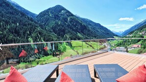 A balcony with wicker furniture overlooking a mountainous landscape. - Hotel & Luxury Appartements Dorfstadl (Kappl)