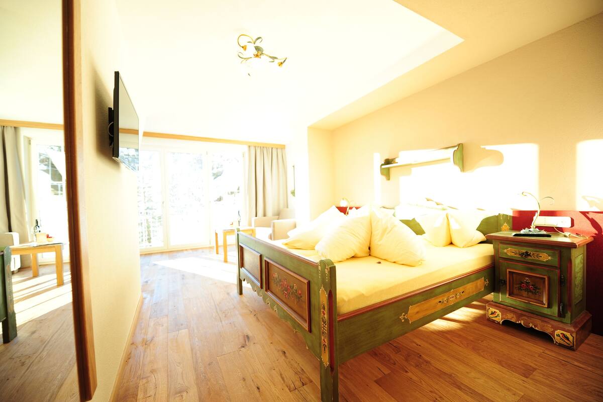 Un dormitorio con una cama de madera, una mesita de noche y un ventanal grande.