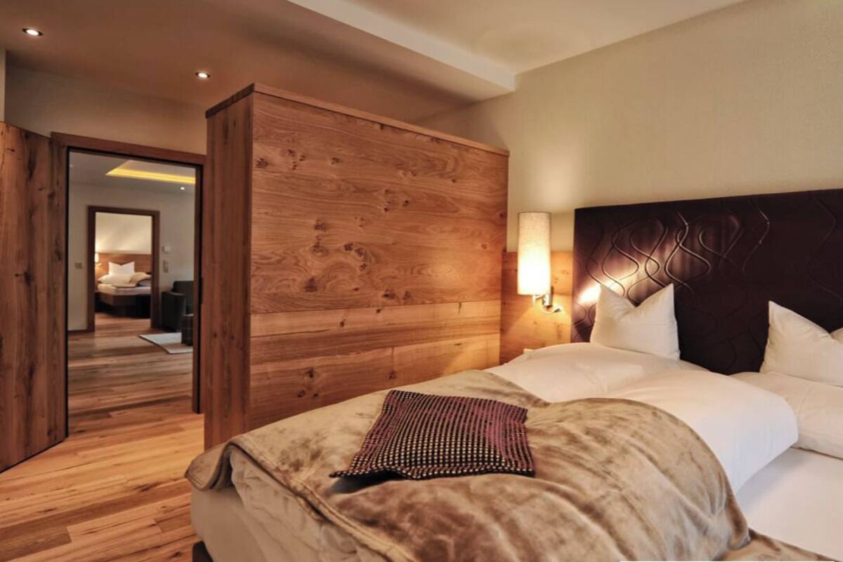 Una habitación de hotel con cabecera de madera, una cama grande con ropa de cama blanca y un armario de madera.