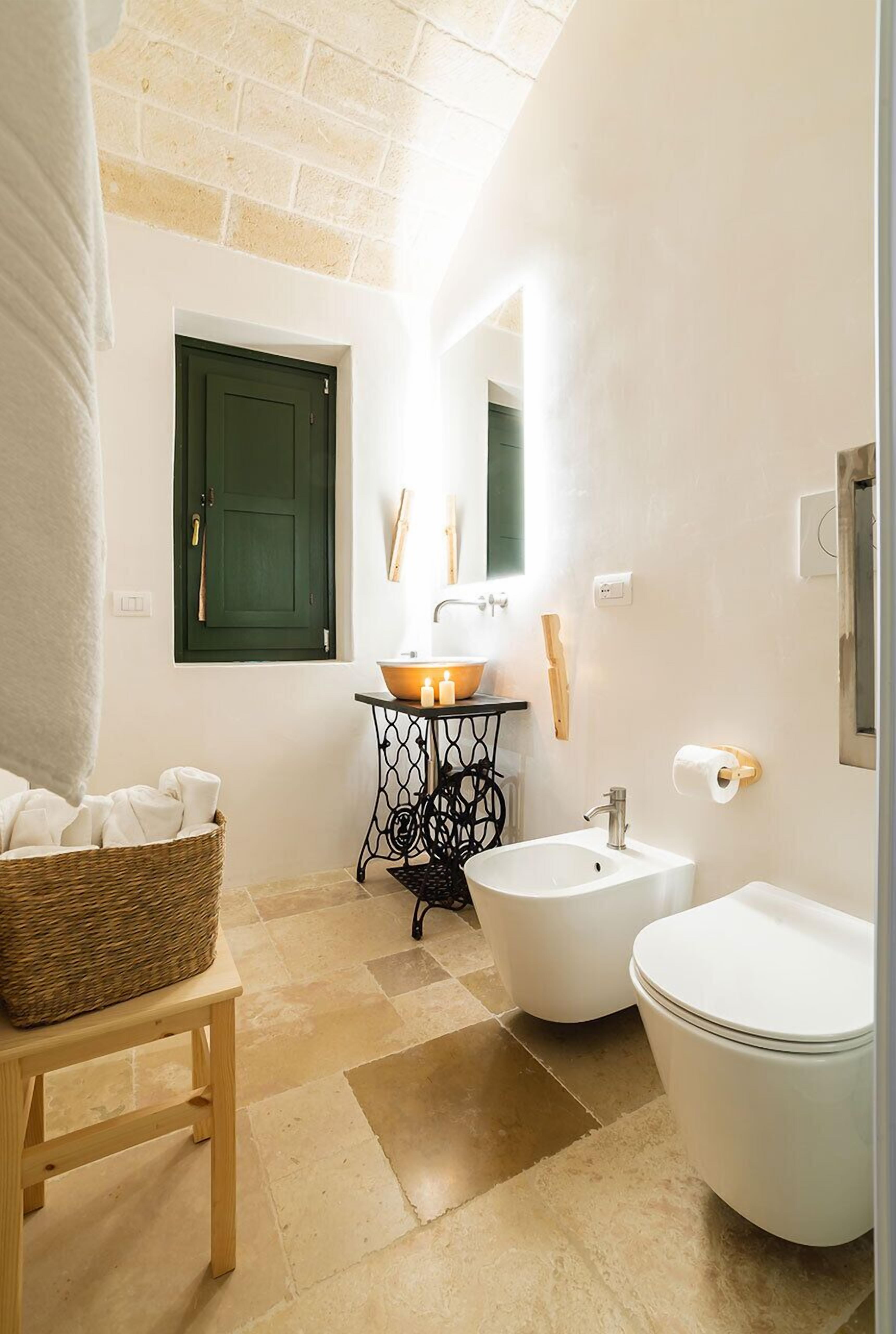 A bathroom with a bathtub, a sink, and a toilet. There is a wicker basket on a wooden stool, a green door, and a mirror above the sink.
