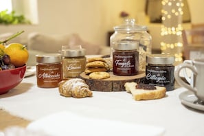 A table with jars of marmellata, cookies, and pastries, along with a bowl of fruit. - Sorelle Barnaba (Monopoli)