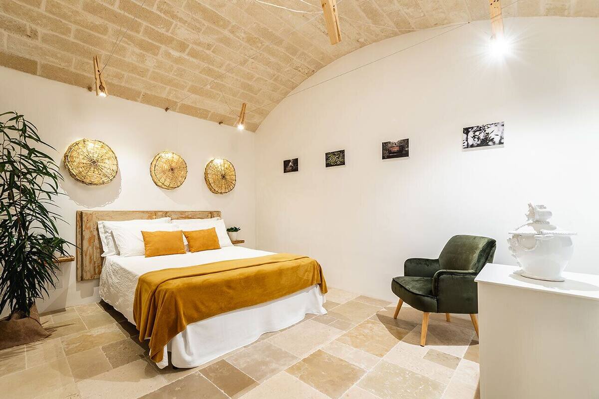 Une chambre à coucher comprenant un lit, une chaise, un bureau et des œuvres d’art murales.