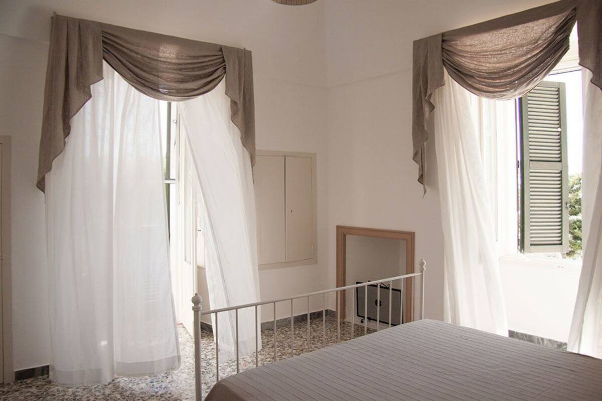 Une chambre à coucher avec un lit, un miroir et des rideaux légers.