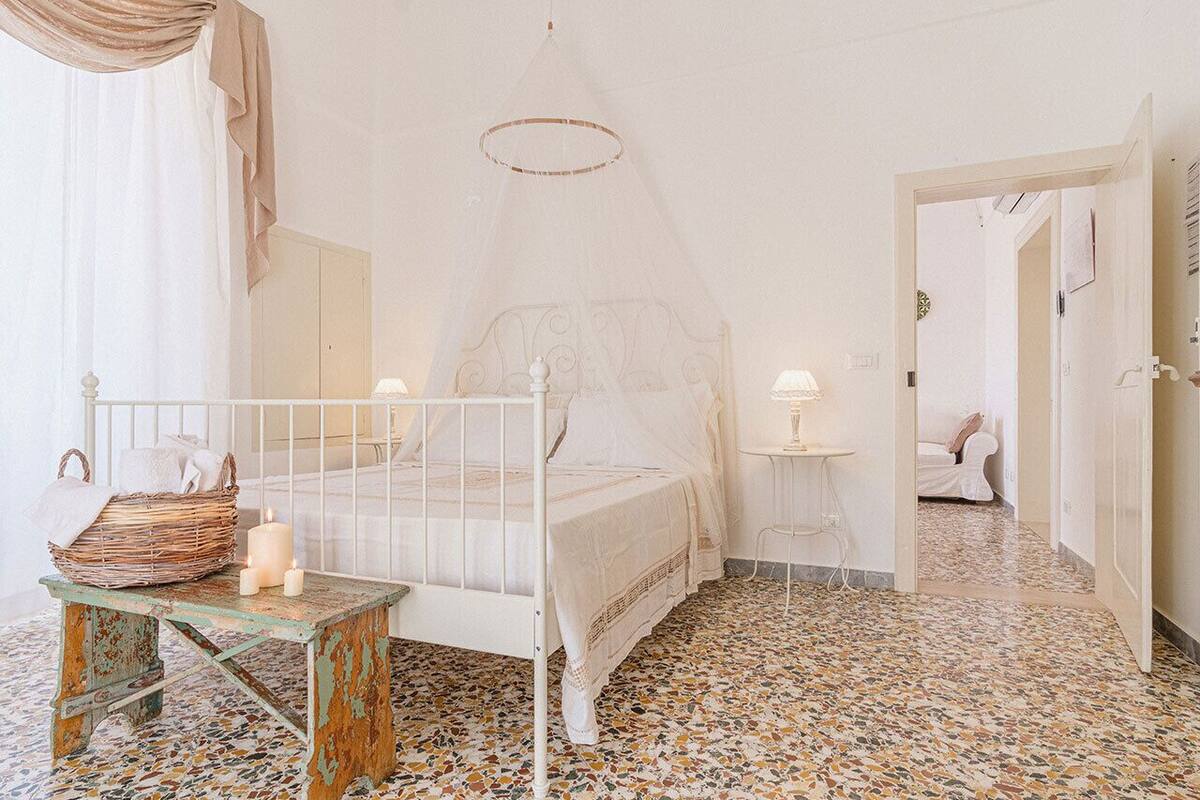 Une chambre à coucher avec un lit à baldaquin, une petite table avec des bougies et un panier en osier.