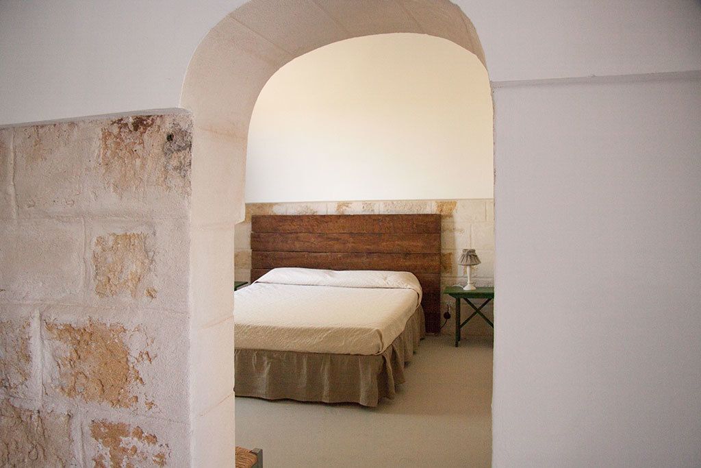 A room with a wooden headboard, a bed, a nightstand, and a lamp.