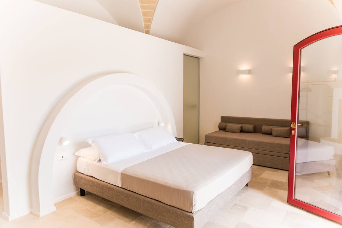 Une chambre à coucher moderne avec un lit, un canapé et une porte en verre.