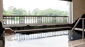 A hot spring area with a stone ledge and metal railing.