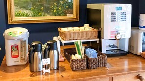 A kitchen counter with a coffee machine, a water dispenser, thermoses, and baskets of items.
