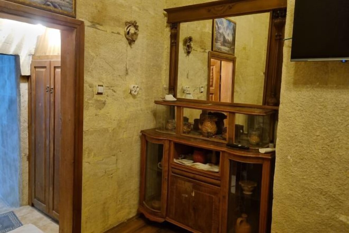 Una stanza con un armadio in legno contenente diversi oggetti, uno specchio e una porta con tenda blu.
