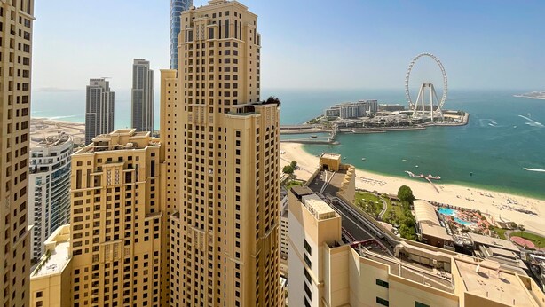 Um edifício alto com vista para uma praia e uma roda-gigante ao longe.
