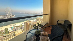 Uma varanda com vista para uma praia, uma roda gigante e um corpo de água.