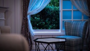 Una habitación con ventana, una silla y una pequeña mesa.